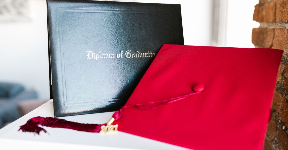 Close-up of a vibrant red graduation cap and diploma, symbolizing achievement.